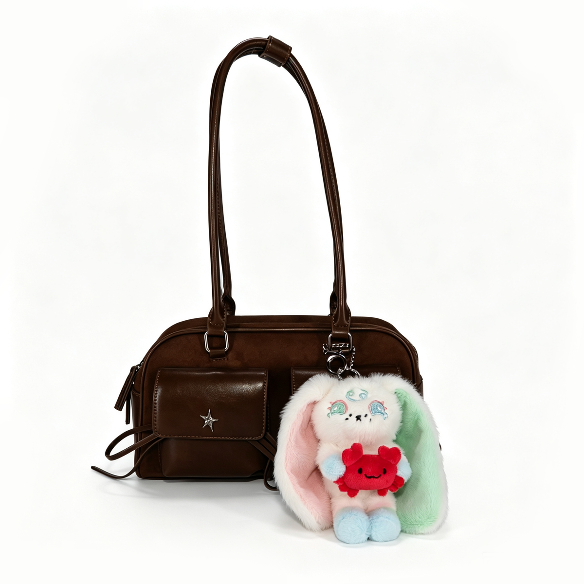 A brown handbag with a star detail and a Cancer Plush Keychain bunny holding a small red plush toy.