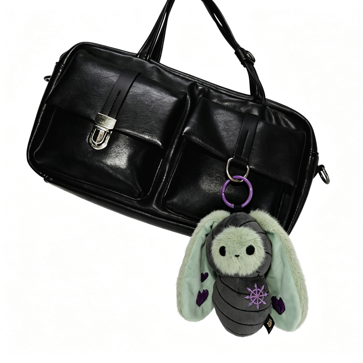 A black handbag with two front pockets and a Bunnculus Plush Keychain bunny attached to one handle.