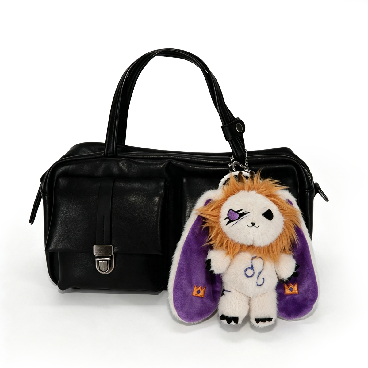A black handbag with a Plushie Dreadfuls Leo Plush Keychain—lion with purple ears and eyepatch—on the handle.