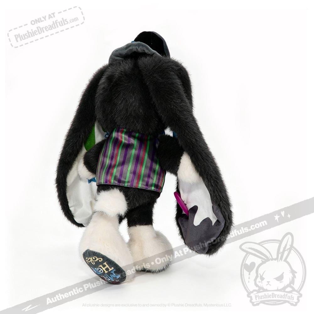 Plushie bunny with long black ears, ADHD Mad Hatter-inspired clothes, and white feet, shown from the back.