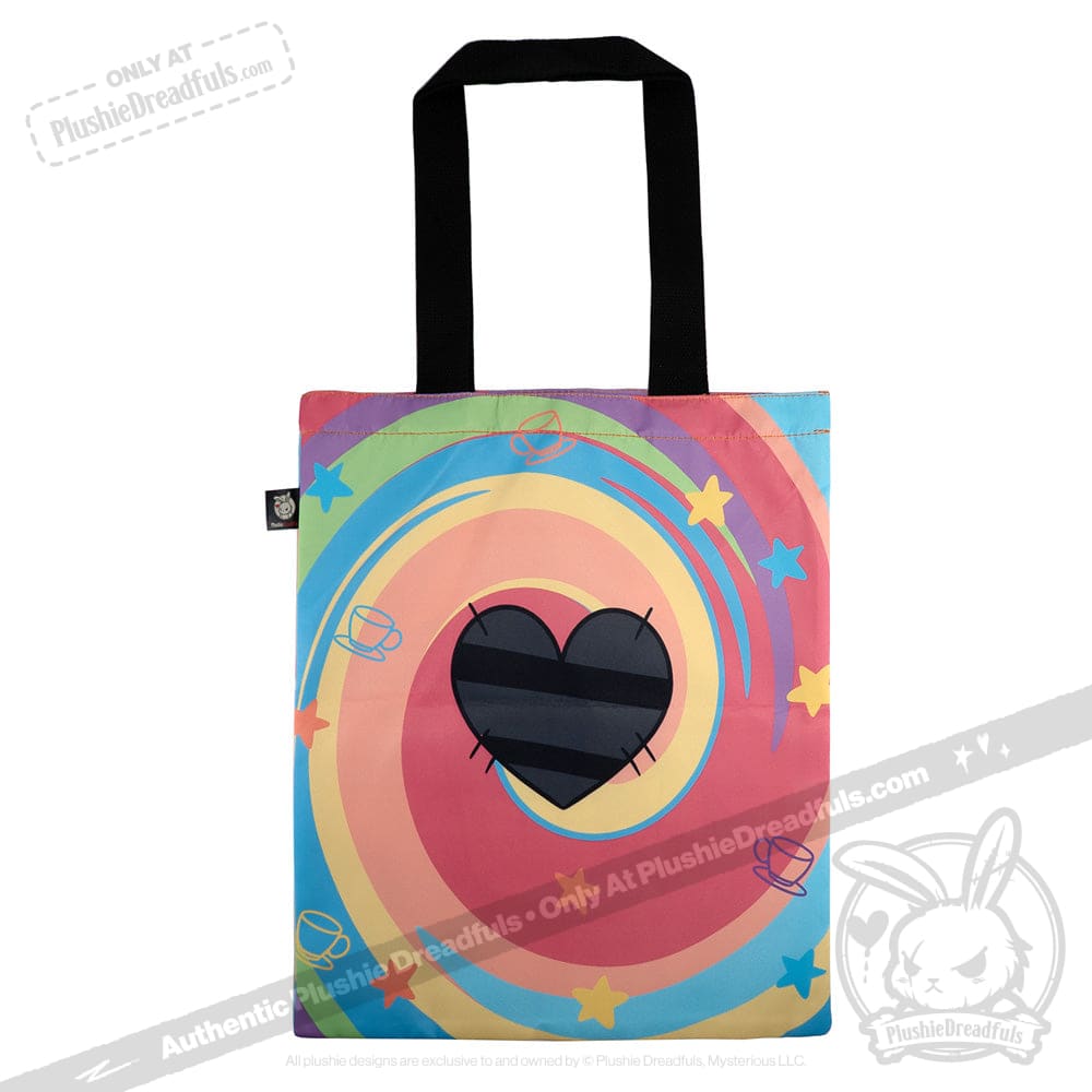 A colorful tote bag with a black heart, swirling stars, rings, and Mad Hatter-inspired cup designs on the front.
