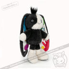 Plush bunny plushie with black and white fur, colorful buttons, and patterns inside its floppy ears—perfect for acceptance.