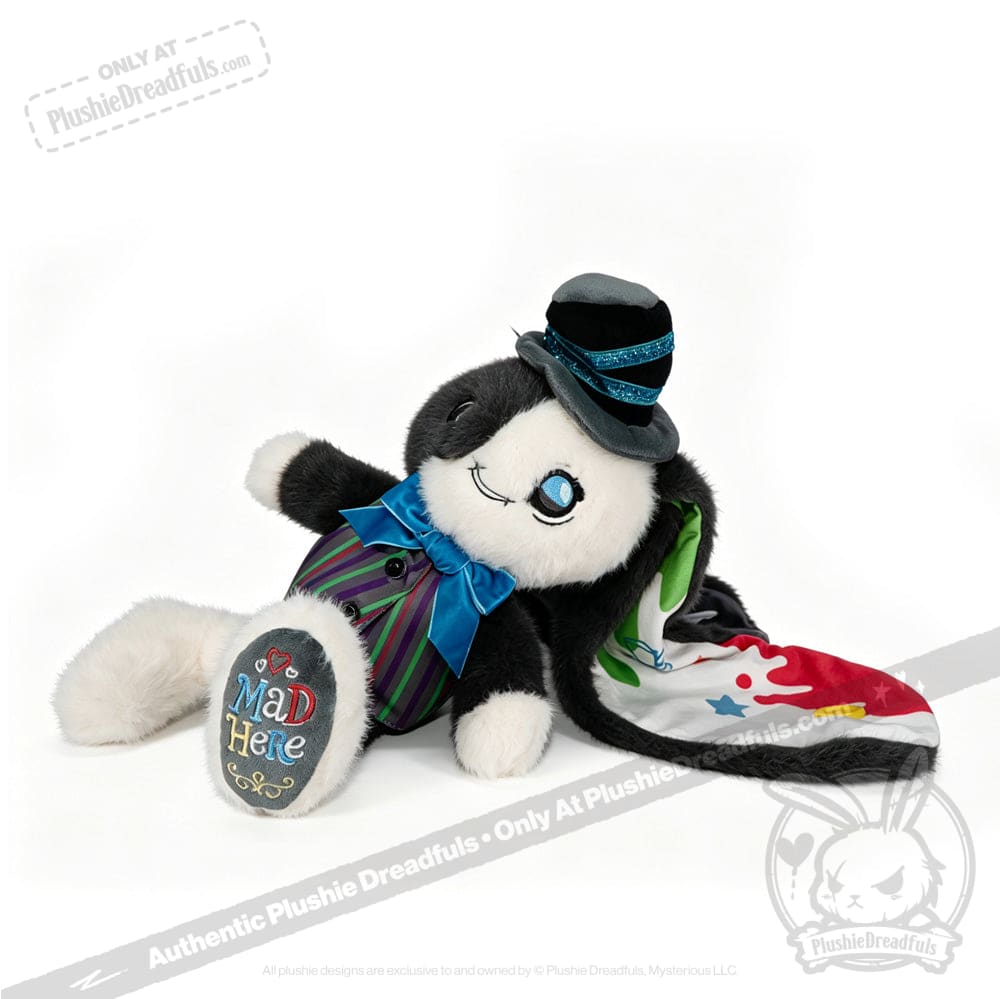 Plushie rabbit in a suit and bow tie, lying down with Mad Here paw—an ADHD Mad Hatter with a colorful cape.
